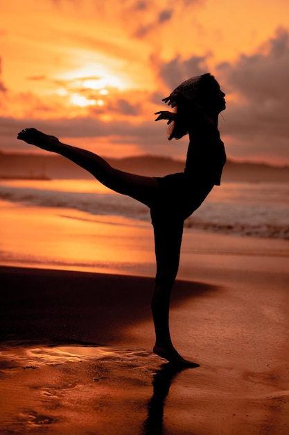 Silhouette of an asian woman practicing her ballet moves on the beach with the waves crashing before the festival starts