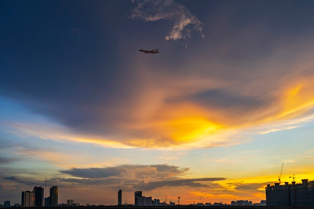 Silhouette of bangkok at sunset with airplane flying in twilight sky