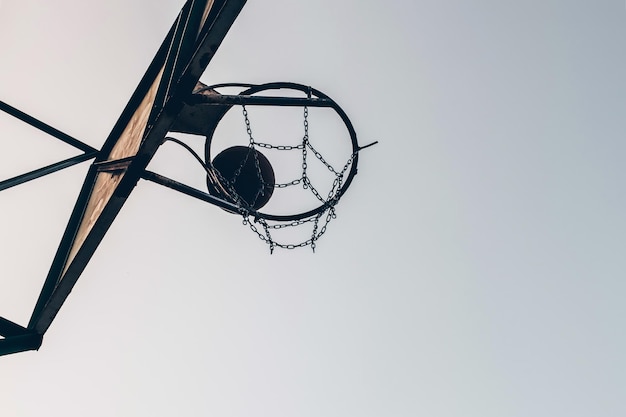 Silhouette of a basketball ball passing a basket on a sky background