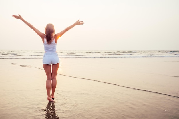 Silhouette of a beautiful girl on the beach ocean. young woman facing the sun enjoying summer holiday romantic