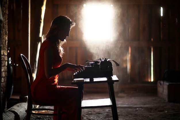 Silhouette of a beautiful girl in a red dress on the background of a window in an old house