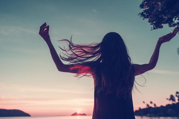 Silhouette of a beautiful slim young woman on bright colorful sunset on a tropical beach