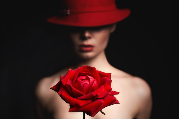 赤いバラの後ろに帽子をかぶった美しい女性のシルエット