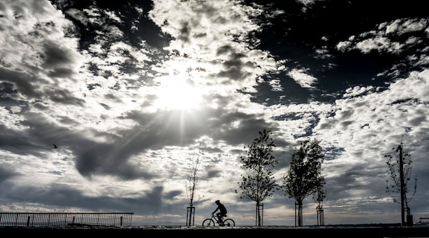 silhouette bicycling against clouds