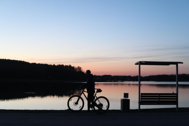 日没時のビーチで自転車に乗る人のシルエット