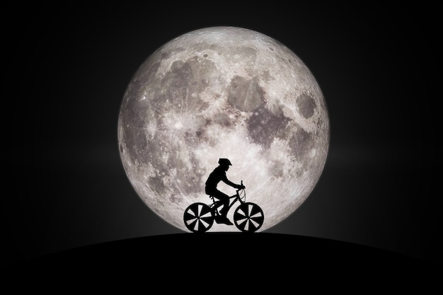 Silhouette of a bike on sky background on full moon.Elements of this image furnished by NASA.