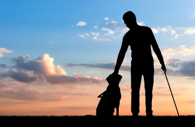 Silhouette of a blind disabled man stroking his dog guide. The concept of blind people with guide dog