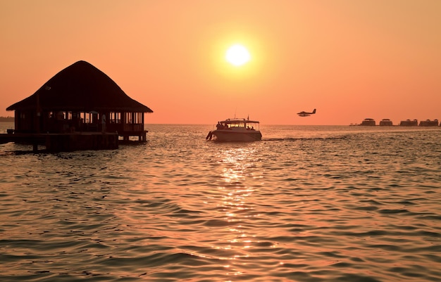 Silhouette of boat boat house and plane in sea