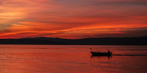 Silhouette boat in calm sea at sunset