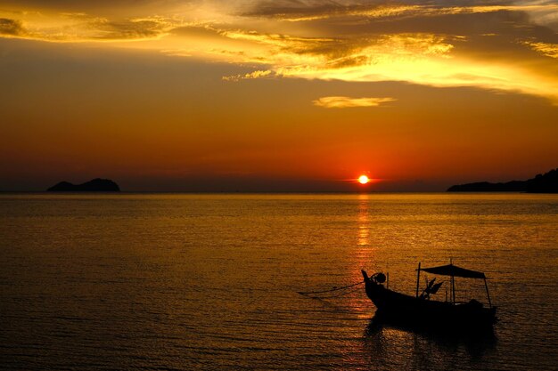 Silhouette boat sailing in sea against sky during sunset