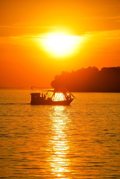 Silhouette boat in sea against orange sky