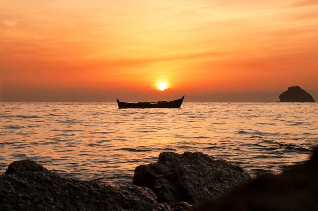 Silhouette boat in sea against sky during sunset