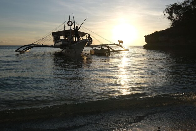 Photo silhouette boat in sea against sky during sunset