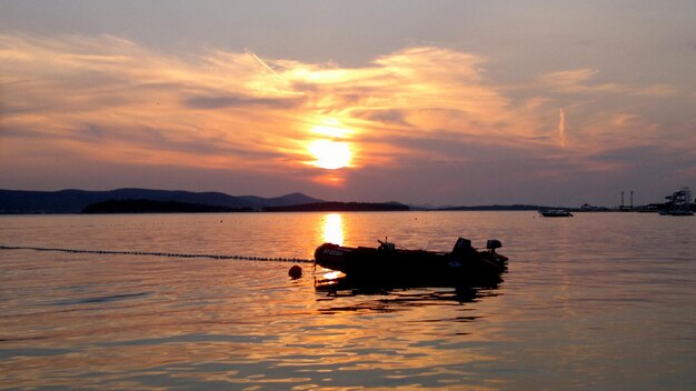 Silhouette boat in sea against sky during sunset