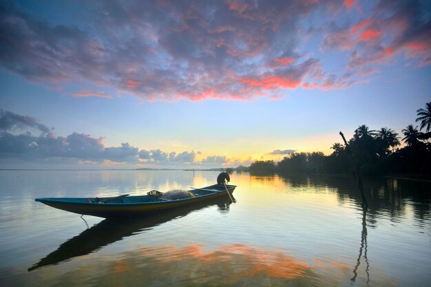 Foto silhouette di barche in un lago calmo al tramonto