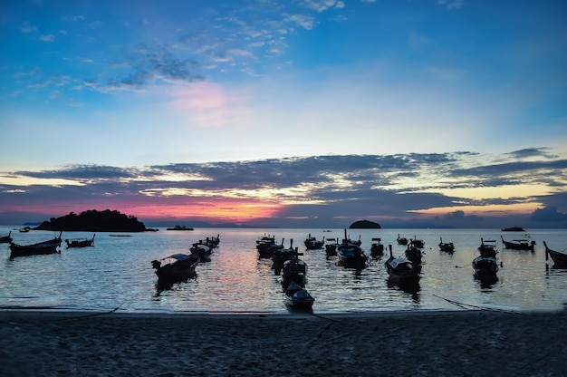 Silhouette boats moored on sea against sky during sunset