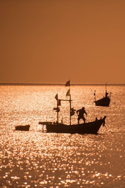 Silhouette boats on sea against clear sky during sunset