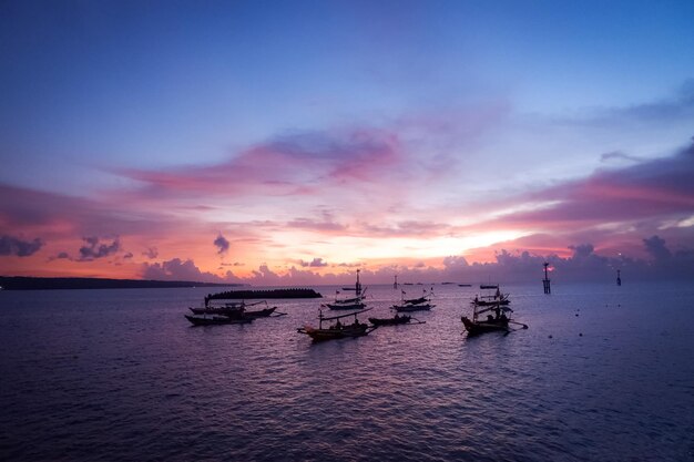 Silhouette boats in sea against sky during sunset