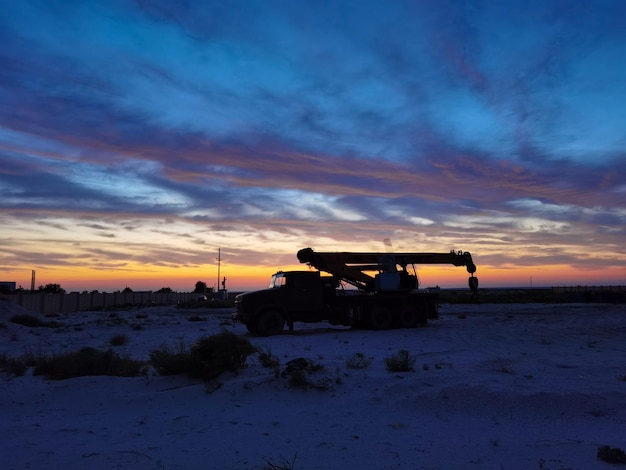 Silhouette of a Boom truck in the oilfield at sunset