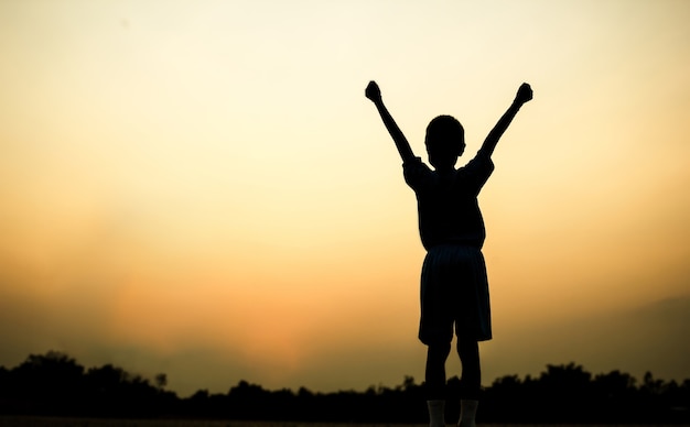 Silhouette of a boy exercising over beautiful sunset background.