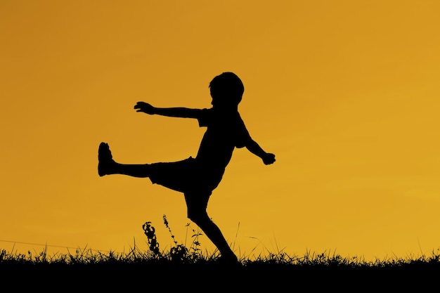 Photo silhouette boy playing against sky during sunset