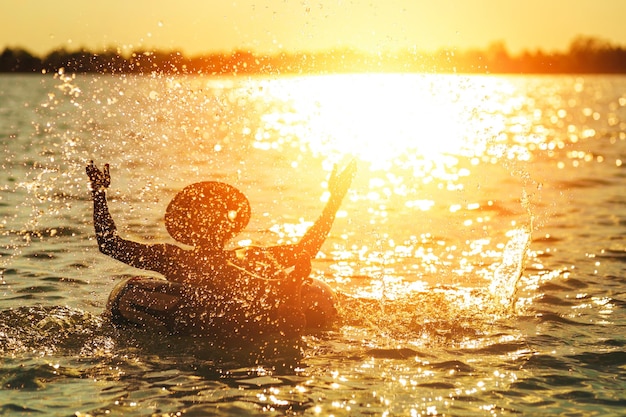 Foto silhouette di un ragazzo in mare contro il cielo durante il tramonto