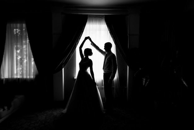 Photo silhouette of bride and groom by the window