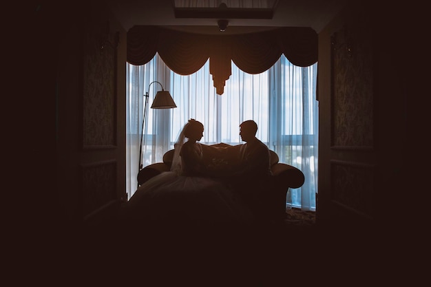 Silhouette of a bride and groom sitting on the couch