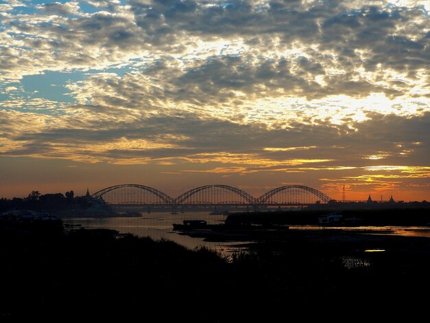 Photo silhouette bridge over river against sky during sunset