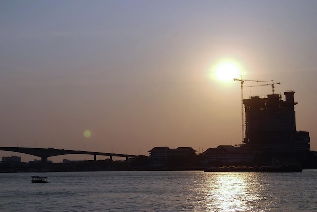 Silhouette bridge over sea against sky during sunset