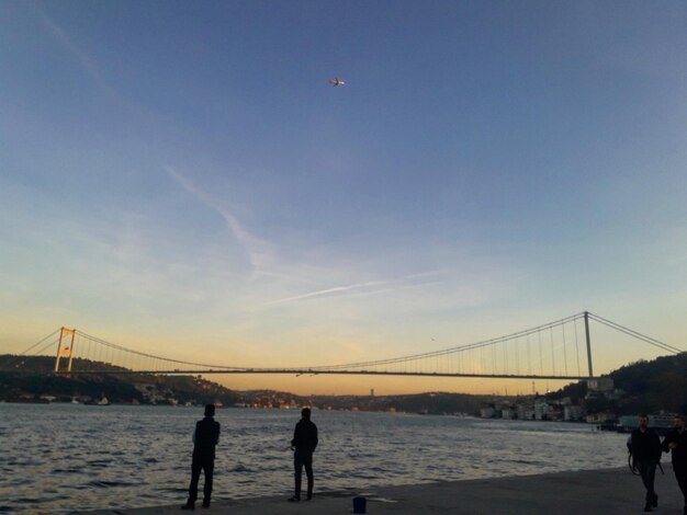 Silhouette bridge over sea against sky during sunset