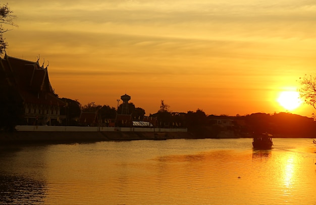 Silhouette of a Buddhist Temple on the Chao Phraya River Bank in Golden Sunset View