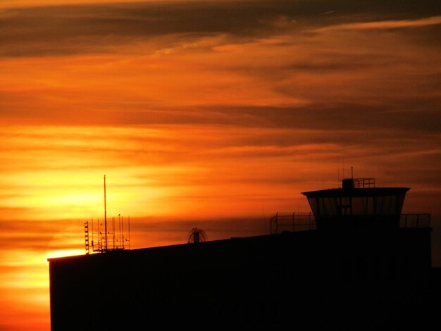 Silhouette building against orange sky