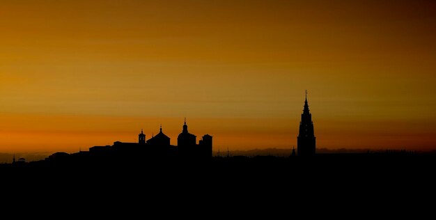 Photo silhouette of building against sky during sunset