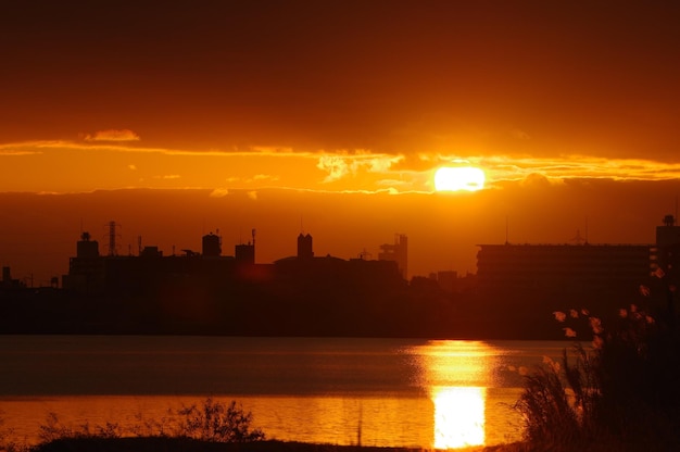 silhouette buildings against orange sky during sunset