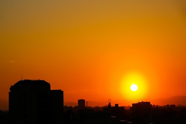 Silhouette buildings against orange sky