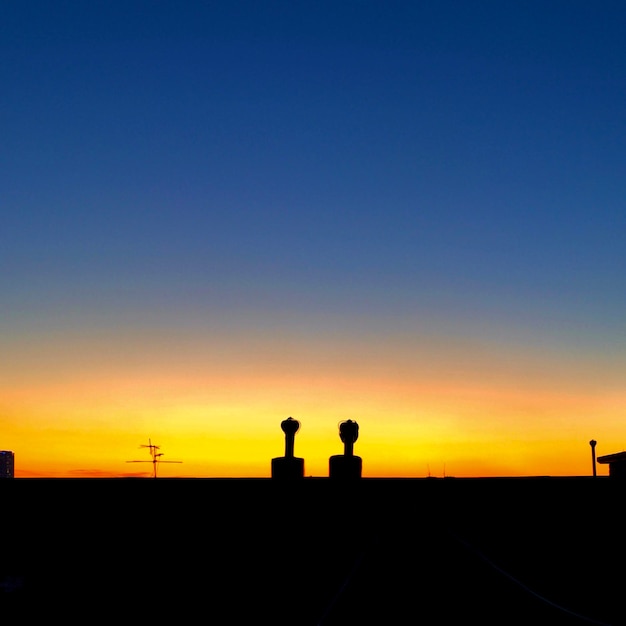 写真 夕暮れの晴れた空を背景に構築されたシルエット