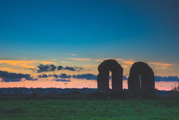 Silhouette built structure on field against sky during sunset