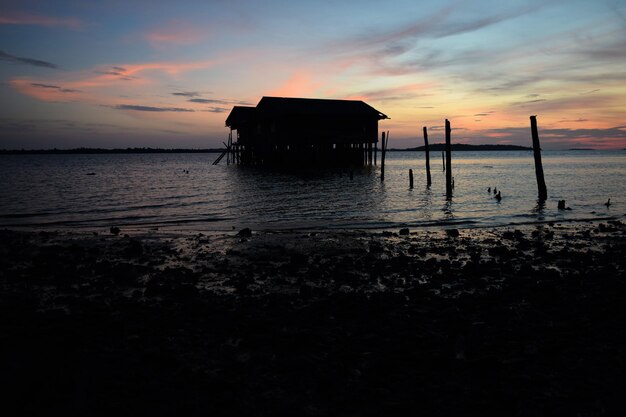 写真 夕暮れの湖の上に建てられたシルエット構造物