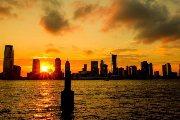 Photo silhouette buoy in sea against buildings in city during sunset