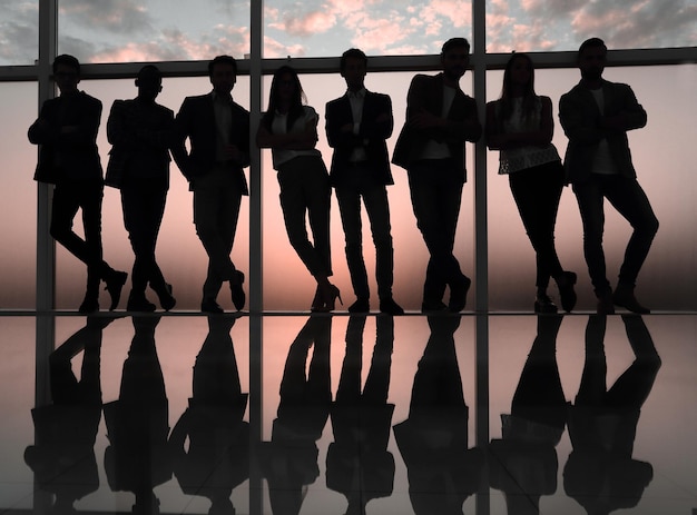 silhouette of a business team standing next to the office window