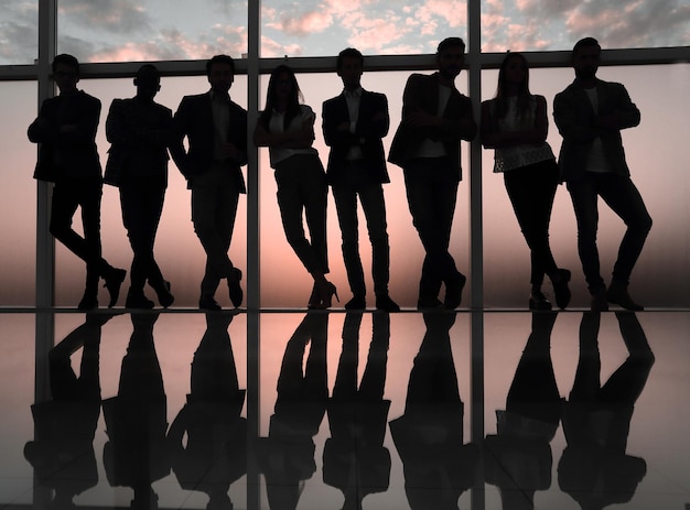 Silhouette of a business team standing next to the office window