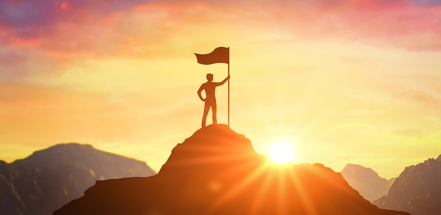 Silhouette of businessman holding flag on top mountain sky and\
sun light background business success and goal concept business man\
with victory flag on hilltop at sunset