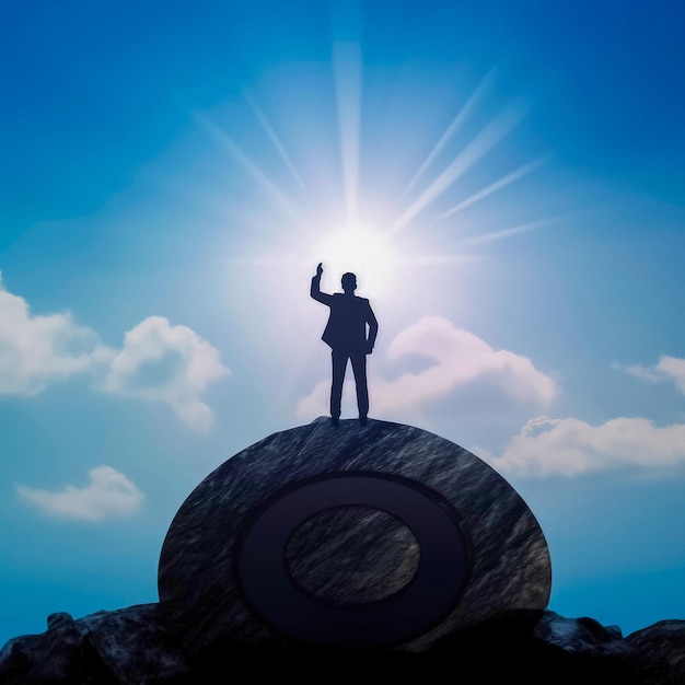 Silhouette of businessman holding target board on the top of mountain with over blue sky