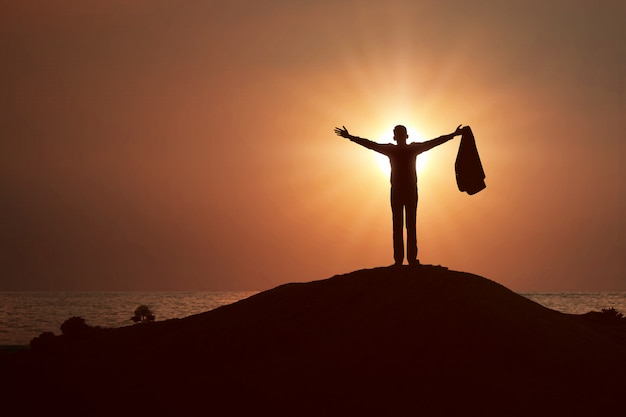 Silhouette of businessman raised hands and praying to god