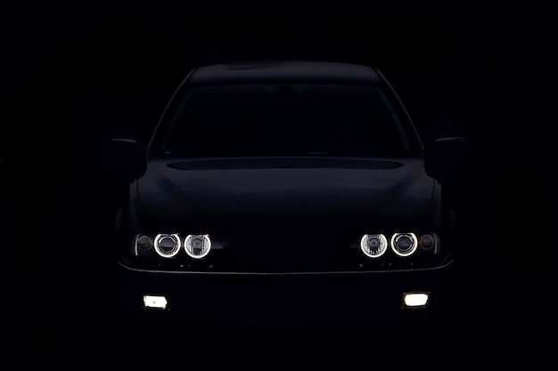 Photo silhouette of car with headlights on black background.