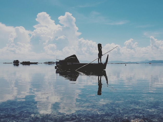 Foto silhouette di un bambino su una barca da pesca