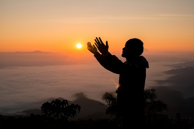 Silhouette of christian man praying at sunset