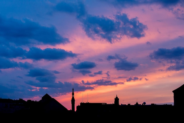 Silhouette of city against cloudy sky during sunset