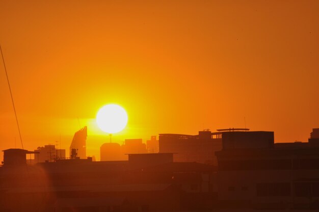 Silhouette city against orange sky during sunset